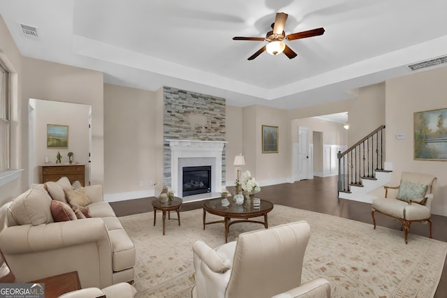 living room with a tray ceiling, a fireplace, ceiling fan, and hardwood / wood-style floors