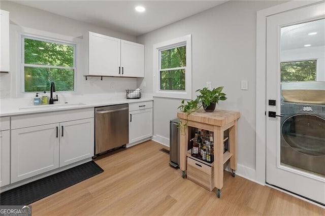 kitchen featuring sink, dishwasher, a wealth of natural light, white cabinets, and light wood-type flooring