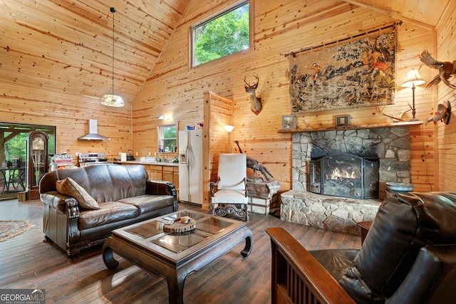 living room featuring a wealth of natural light, a fireplace, high vaulted ceiling, and wood walls