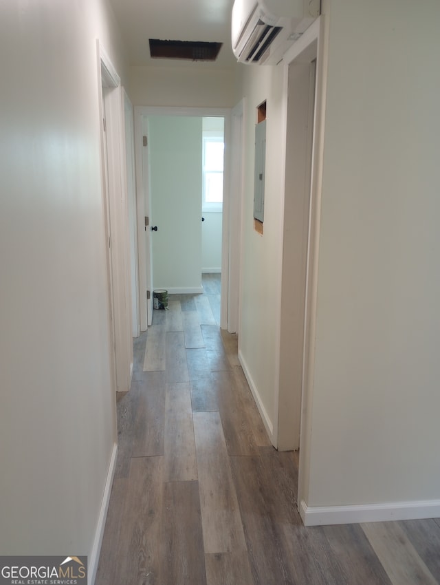 hallway featuring electric panel, a wall unit AC, and hardwood / wood-style floors