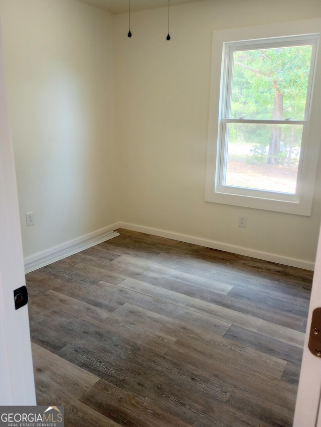 empty room featuring dark hardwood / wood-style flooring and a healthy amount of sunlight