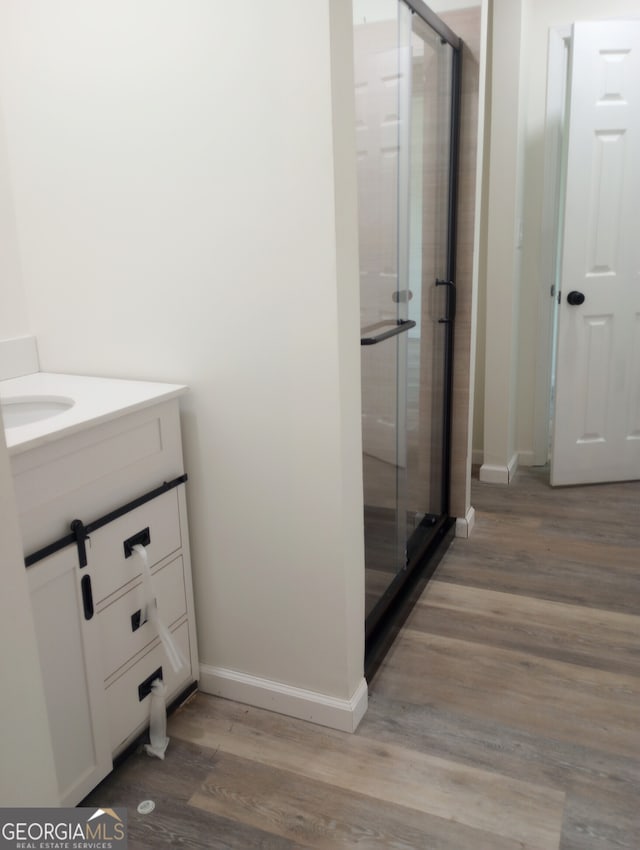 bathroom with walk in shower, hardwood / wood-style flooring, and vanity