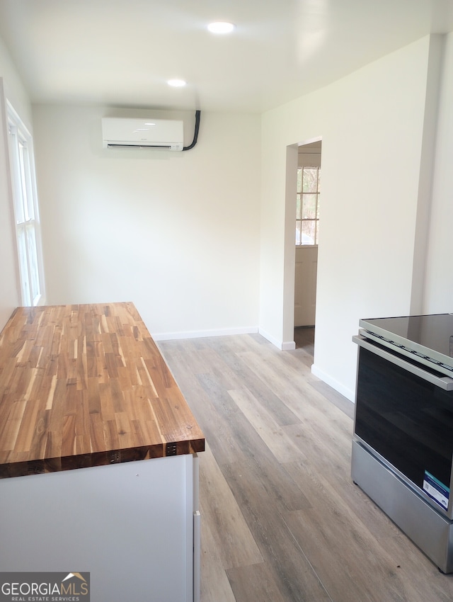 kitchen with electric range, wood counters, a wall mounted air conditioner, and hardwood / wood-style floors