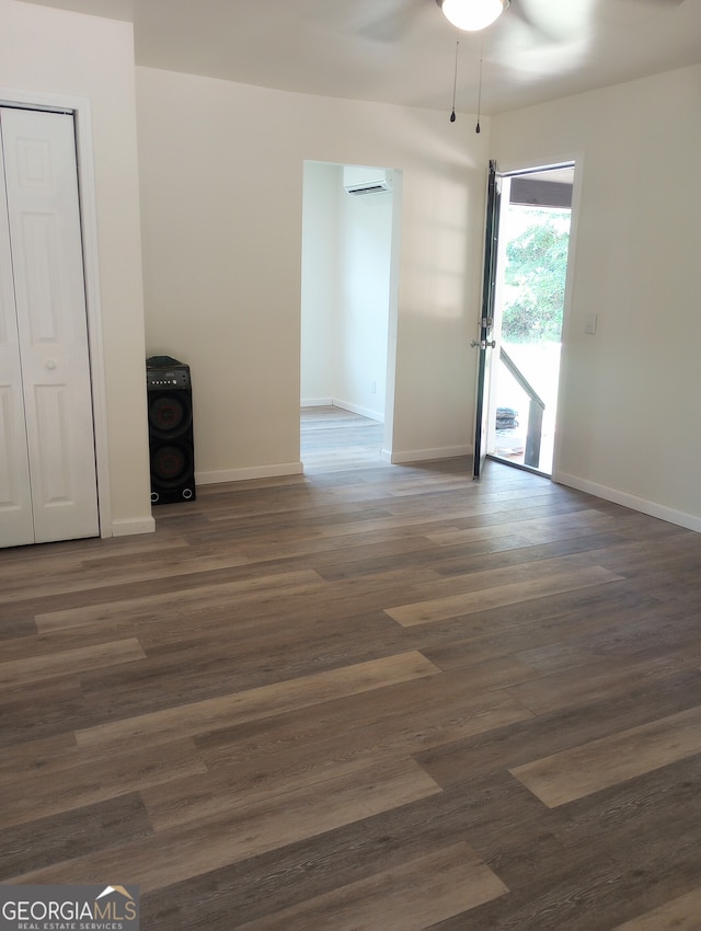 interior space with dark wood-type flooring, a wall mounted AC, and ceiling fan