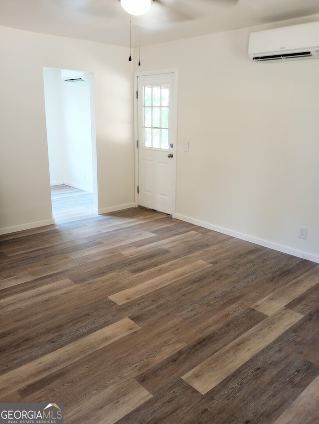 empty room featuring dark wood-type flooring, an AC wall unit, and ceiling fan