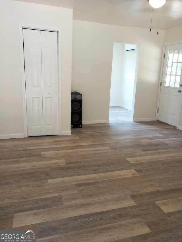 unfurnished bedroom with a wall mounted AC, dark hardwood / wood-style flooring, and a closet