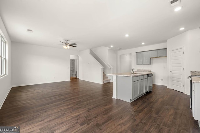 kitchen featuring sink, gray cabinetry, a center island with sink, stainless steel dishwasher, and dark hardwood / wood-style flooring