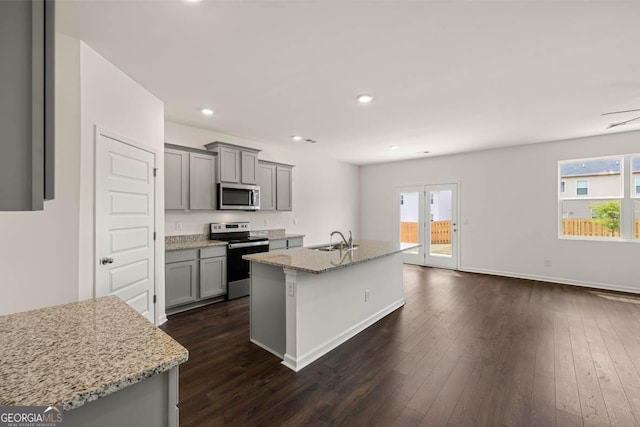 kitchen with sink, a center island with sink, appliances with stainless steel finishes, gray cabinets, and light stone countertops