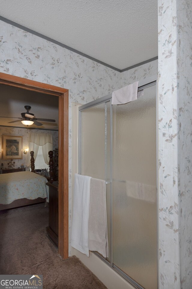 bathroom with ceiling fan, crown molding, a shower with door, and a textured ceiling