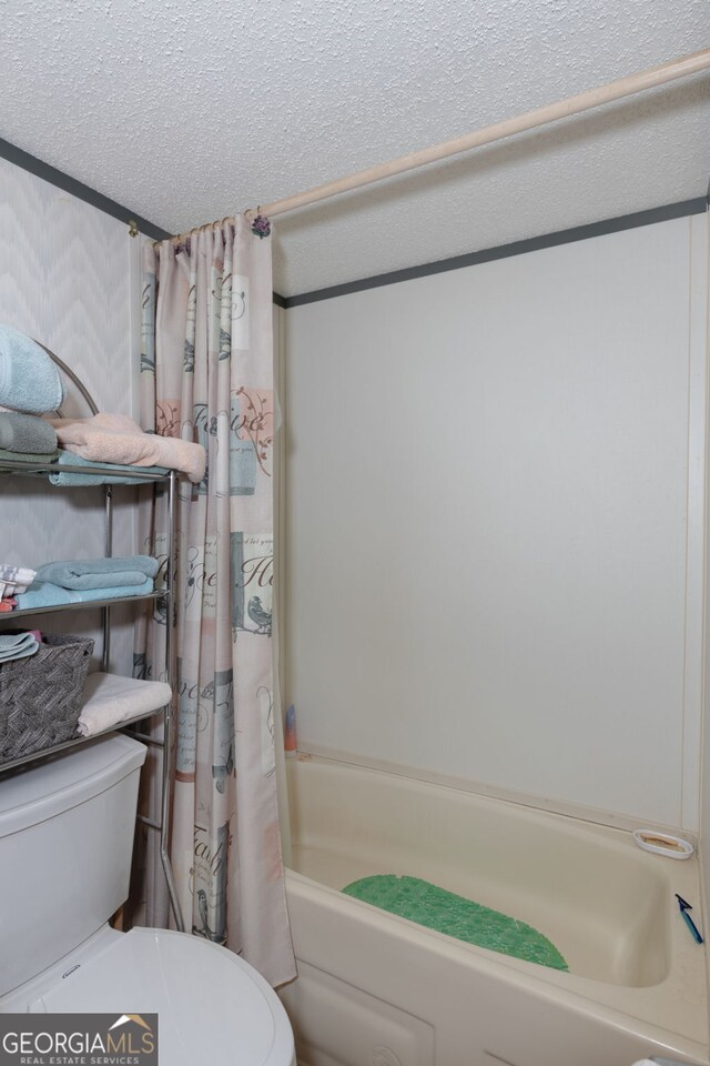 bathroom with shower / bath combination with curtain, toilet, and a textured ceiling