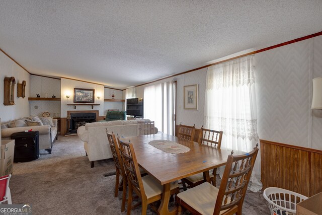 carpeted dining space with ornamental molding and a textured ceiling