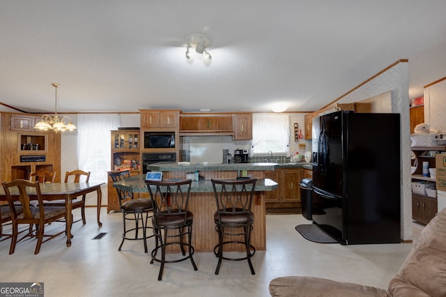 kitchen with pendant lighting, a breakfast bar area, ornamental molding, a notable chandelier, and black appliances