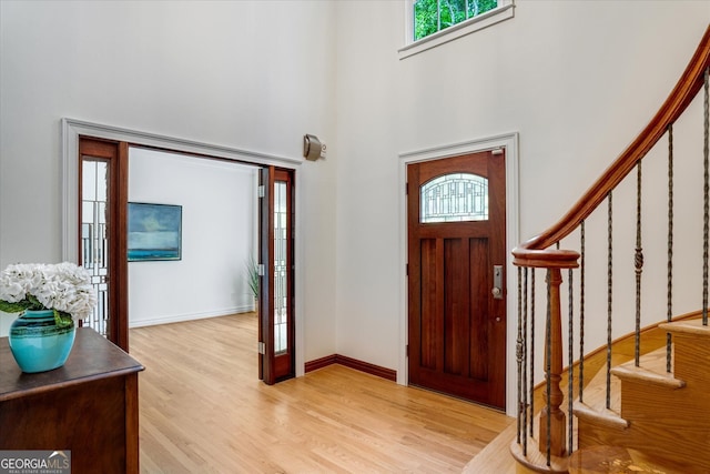 foyer entrance featuring light hardwood / wood-style flooring and a towering ceiling