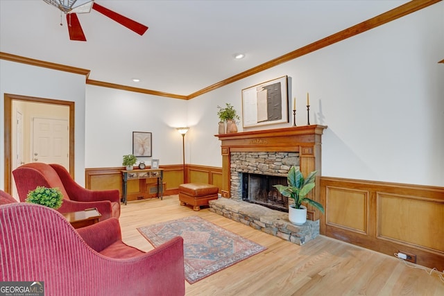 living room with a fireplace, ceiling fan, hardwood / wood-style floors, and crown molding