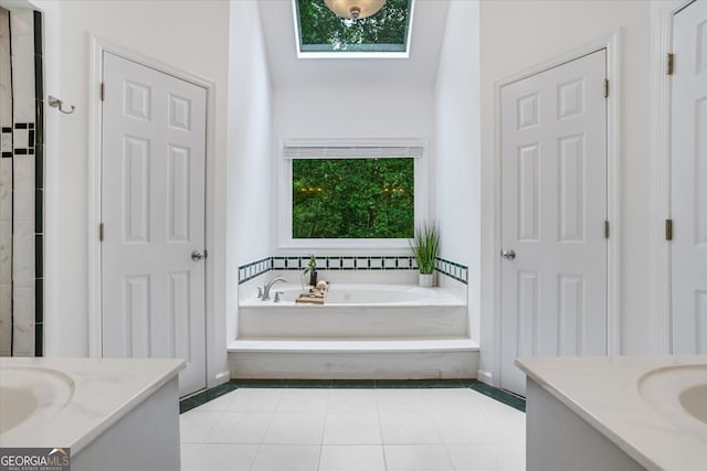 bathroom with tile patterned flooring, a washtub, a skylight, and vanity