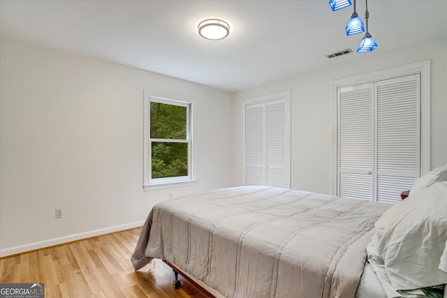 bedroom featuring light hardwood / wood-style floors and multiple closets