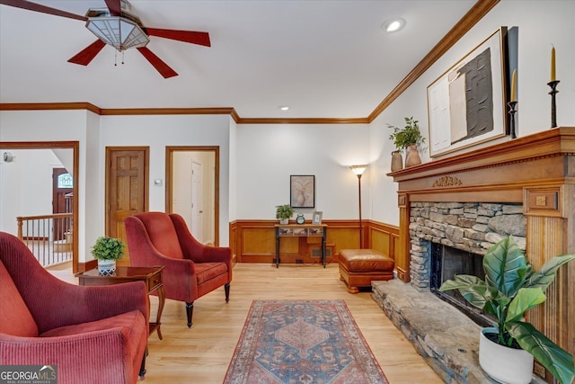 living room featuring light hardwood / wood-style flooring, a fireplace, ceiling fan, and crown molding