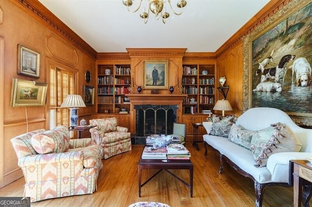 living area featuring built in features, a fireplace, light wood-type flooring, and ornamental molding