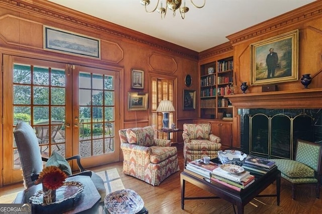 living area with french doors, built in features, light wood-type flooring, and an inviting chandelier