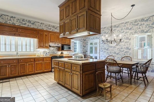 kitchen featuring pendant lighting, crown molding, stove, and light tile patterned floors