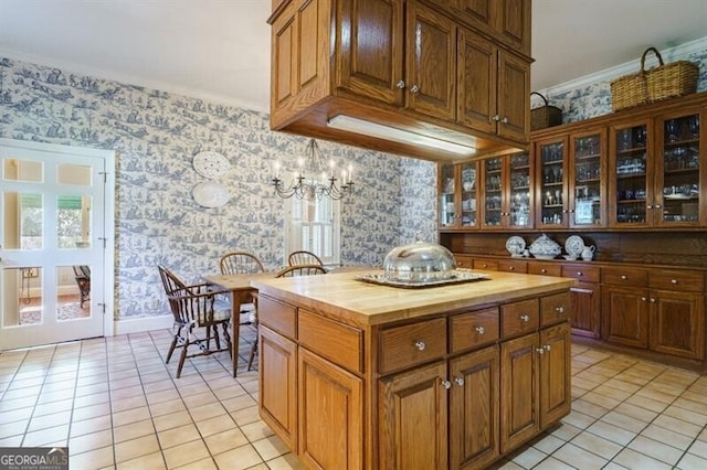 kitchen featuring light tile patterned floors, a kitchen island, crown molding, and butcher block counters