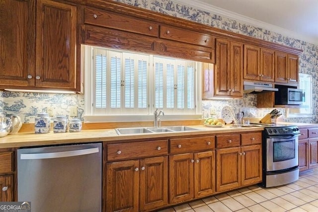 kitchen with light tile patterned floors, backsplash, stainless steel appliances, sink, and ornamental molding