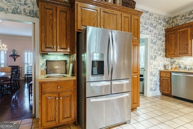 kitchen with tasteful backsplash, stainless steel appliances, ornamental molding, and light tile patterned floors