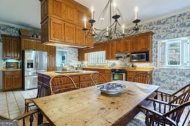 kitchen with appliances with stainless steel finishes, decorative light fixtures, light tile patterned floors, decorative backsplash, and ornamental molding