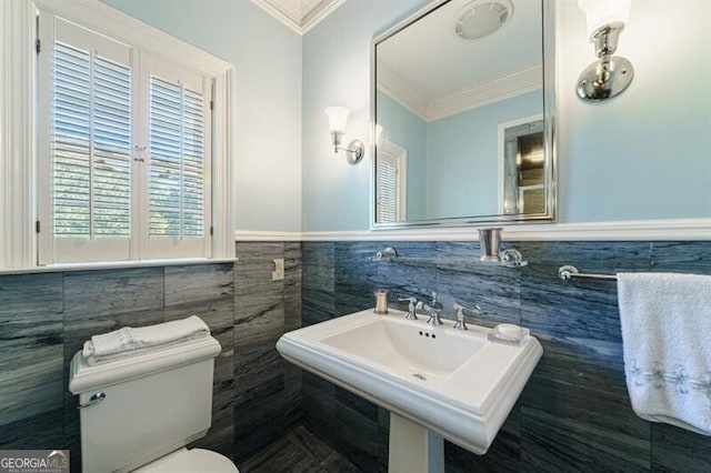 bathroom featuring ornamental molding, sink, toilet, and tile walls