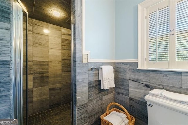 bathroom featuring toilet, an enclosed shower, and tile walls