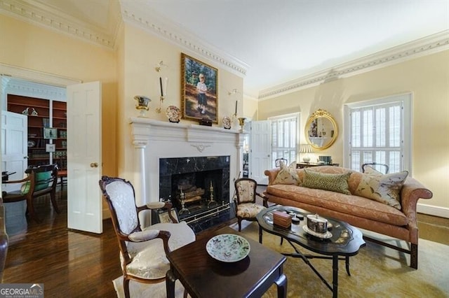 living room with built in shelves, crown molding, hardwood / wood-style floors, and a high end fireplace