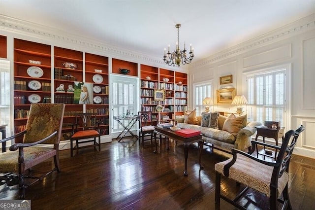 living area featuring a notable chandelier, dark hardwood / wood-style flooring, built in features, and crown molding