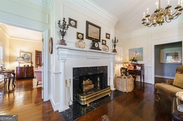 living room featuring an inviting chandelier, dark hardwood / wood-style floors, a premium fireplace, and ornamental molding