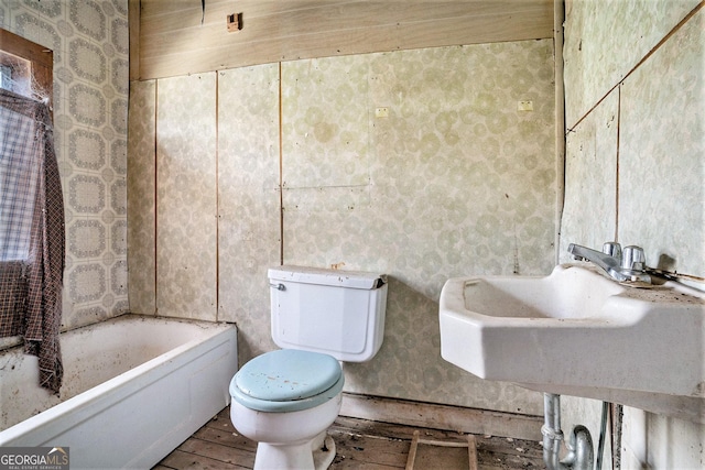 bathroom featuring toilet, a tub, and sink