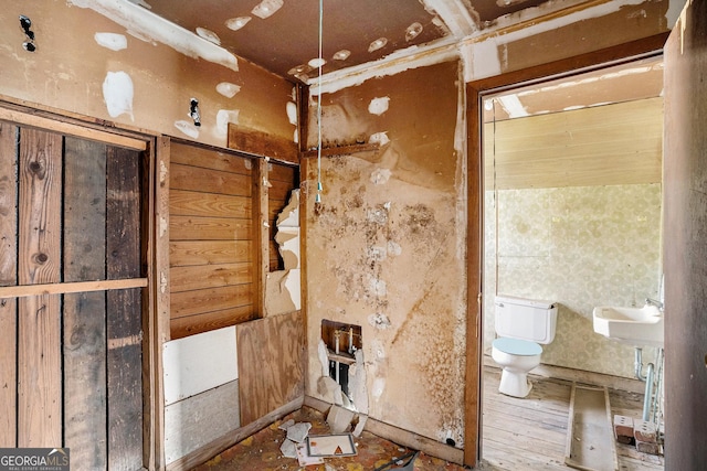 bathroom featuring toilet and wood walls