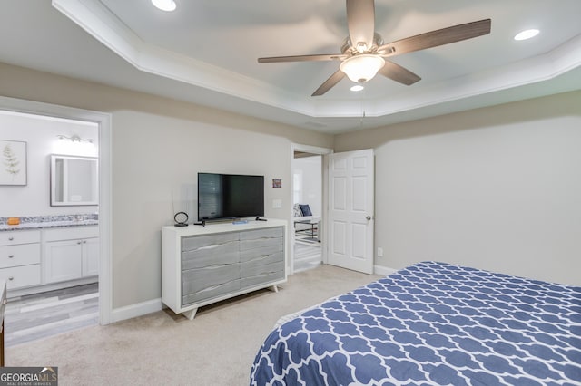 carpeted bedroom with crown molding, ceiling fan, connected bathroom, and a tray ceiling