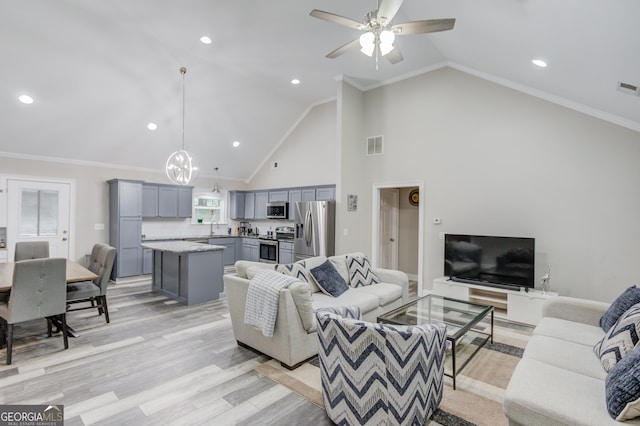 living room featuring high vaulted ceiling, ornamental molding, light hardwood / wood-style floors, and sink