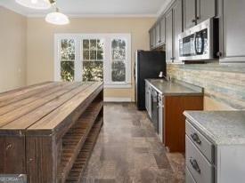 kitchen with gray cabinetry, refrigerator, hanging light fixtures, decorative backsplash, and ornamental molding