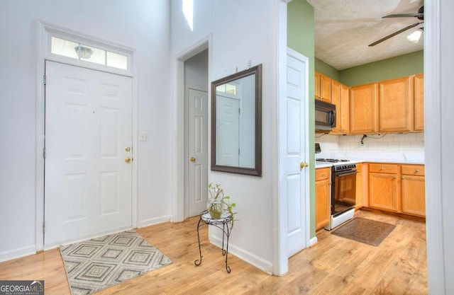 entryway with a textured ceiling, light wood-type flooring, and ceiling fan