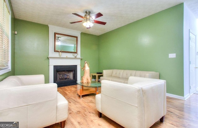 living room featuring a textured ceiling, a fireplace, wood-type flooring, and ceiling fan