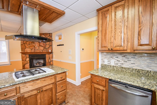 kitchen with light stone counters, island range hood, white gas stovetop, dishwasher, and backsplash