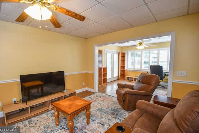 tiled living room with ceiling fan and a drop ceiling