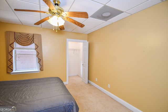 bedroom with ceiling fan, a closet, light carpet, and a drop ceiling