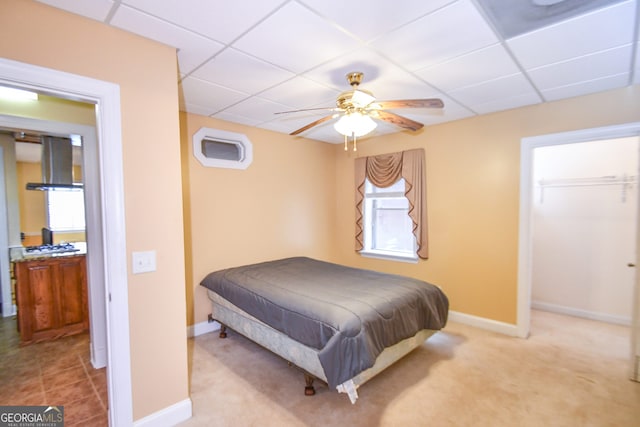 bedroom with light carpet, a paneled ceiling, and ceiling fan