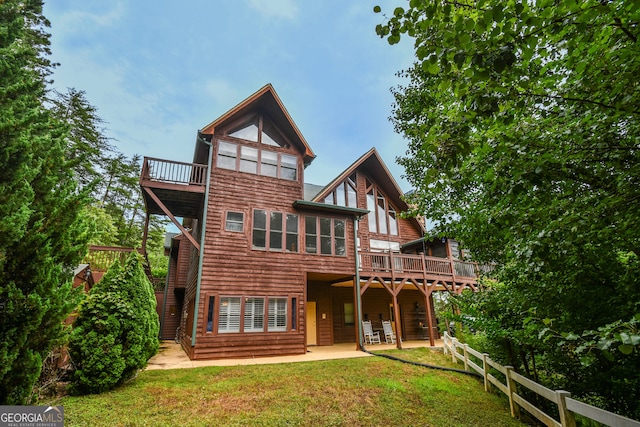 rear view of property with a deck, a patio area, and a lawn