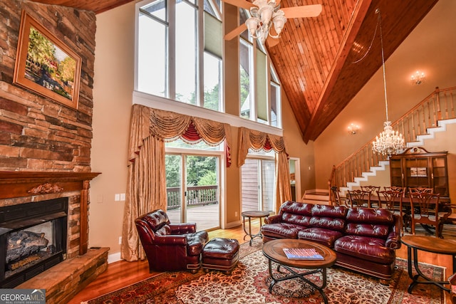 living room featuring a stone fireplace, wood ceiling, high vaulted ceiling, hardwood / wood-style flooring, and ceiling fan with notable chandelier