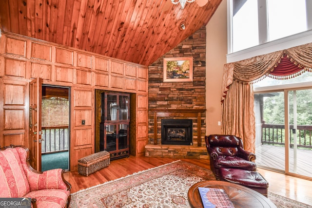 living room featuring a stone fireplace, hardwood / wood-style floors, wooden ceiling, and high vaulted ceiling