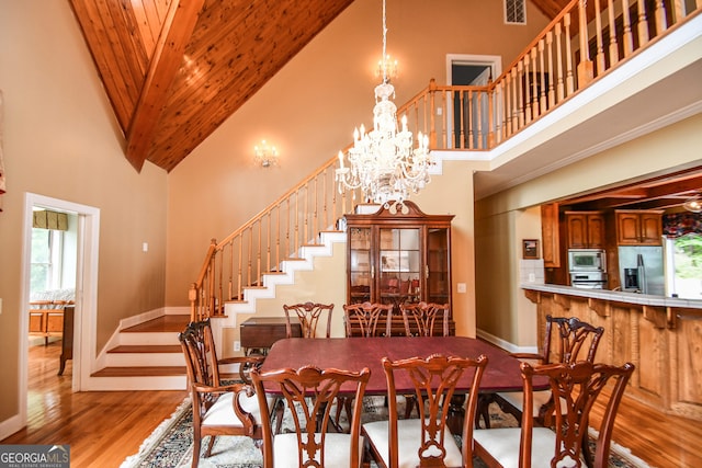 dining space with wood ceiling, a notable chandelier, high vaulted ceiling, and light wood-type flooring