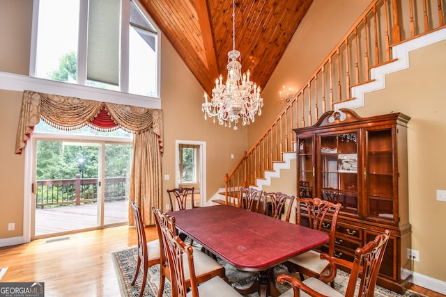 dining room featuring wood ceiling, a towering ceiling, a chandelier, and light wood-type flooring