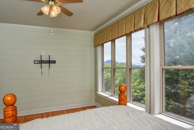 bedroom featuring crown molding, wooden walls, and light hardwood / wood-style floors